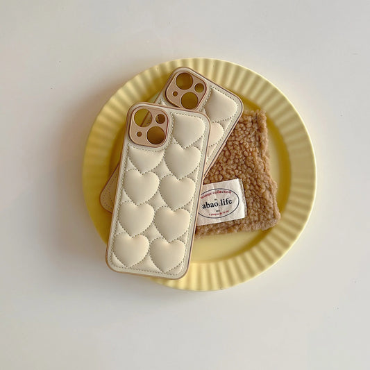Two phone cases with a heart pattern and a small pouch on a yellow plate.