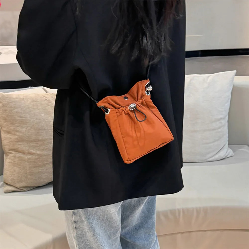 Person wearing a black coat with an orange drawstring bag attached, sitting on a couch.