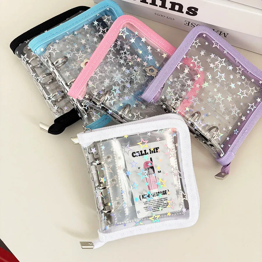 Four clear plastic ring binder pouches with star-patterned vinyl inserts, shown in black, blue, pink, and purple trim, arranged on a light beige surface.