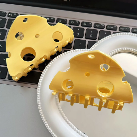 A gold-colored acrylic hair claw clip designed to look like a slice of cheese.