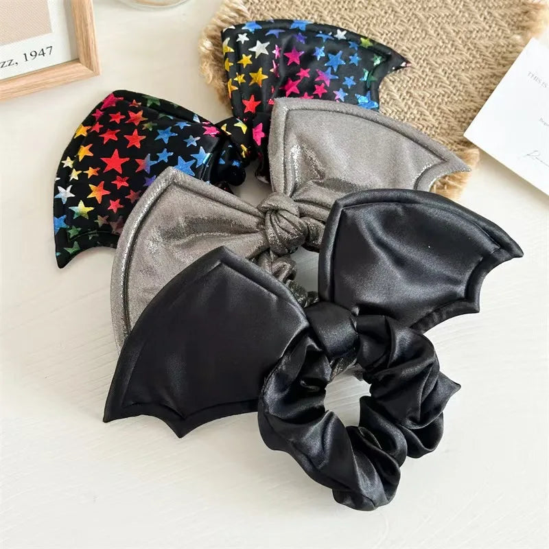 Set of bat-wing shaped hair scrunchies in black, gray, and multicolor star pattern on a light background.