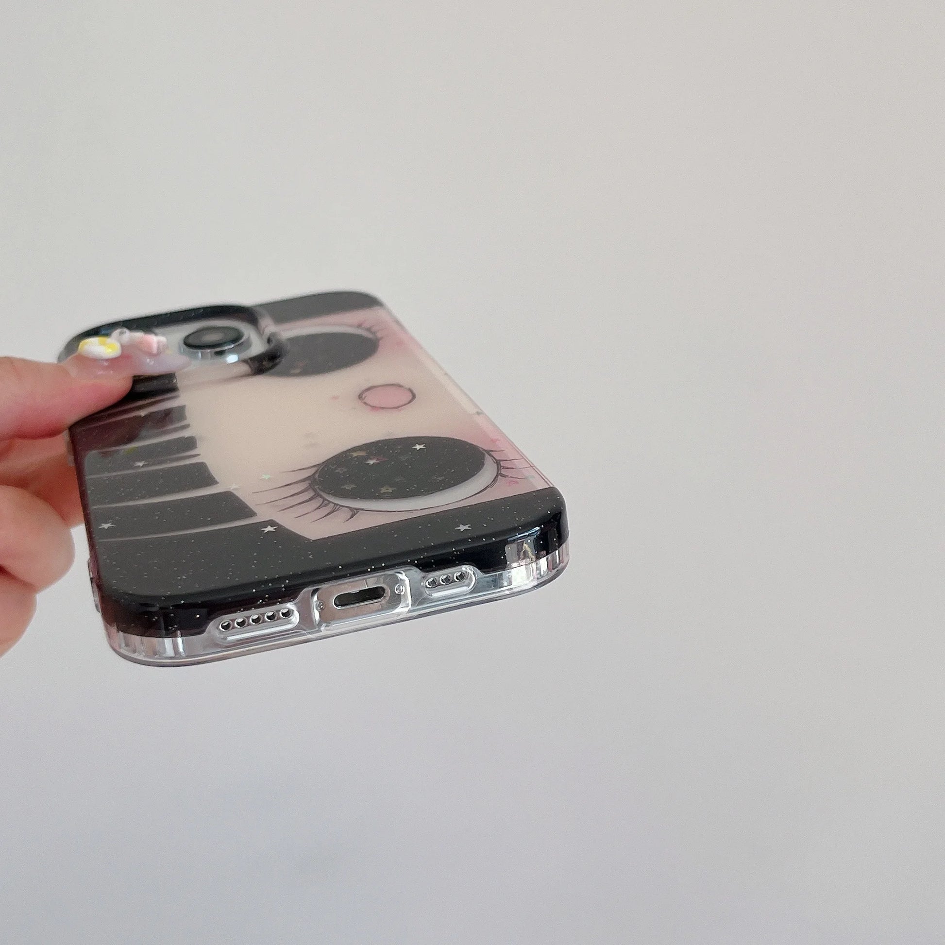 Phone case with cartoon design held by a hand on a light gray background