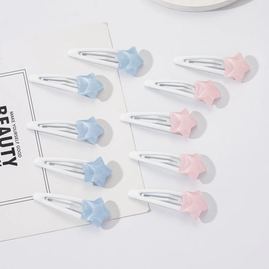 Nine white hair claw clips with star-shaped ends in pastel blue and pink, arranged on a white surface with a decorative card.