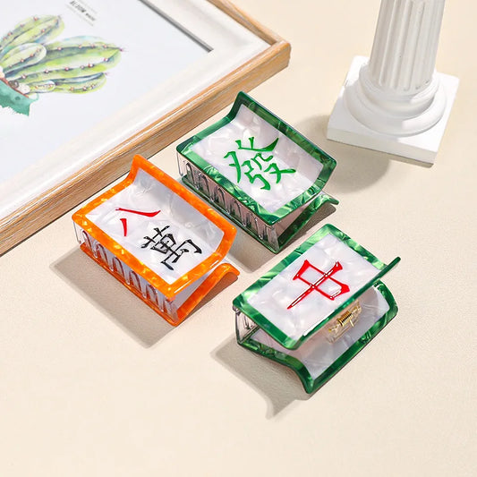 Three small rectangular hair claws shaped like Mahjong tiles with Chinese characters on a light surface.