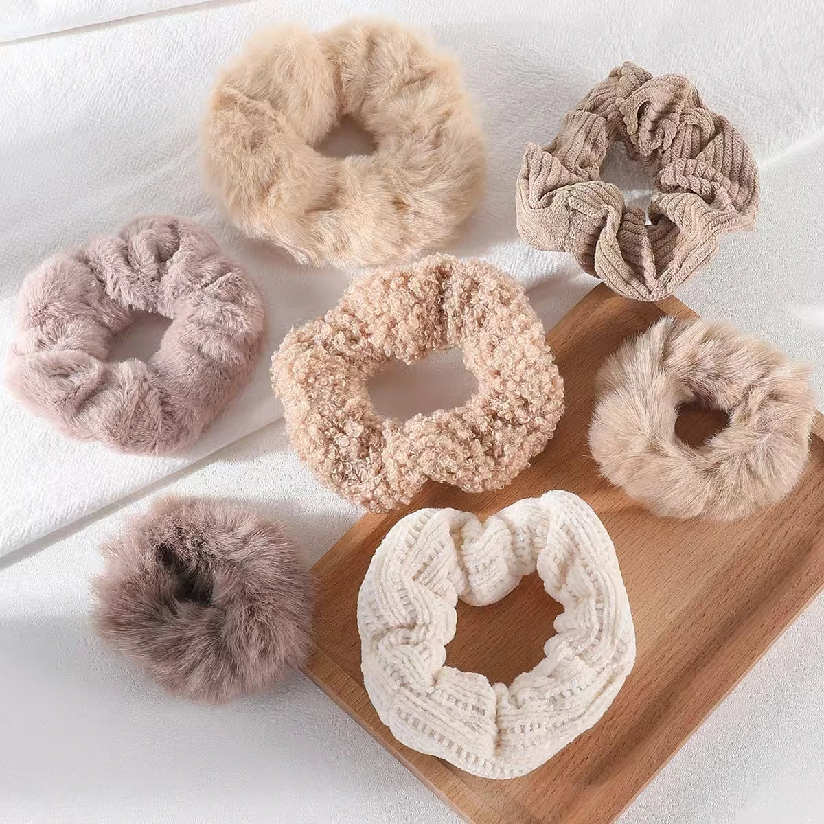Collection of various textured scrunchies on a wooden board with a white background