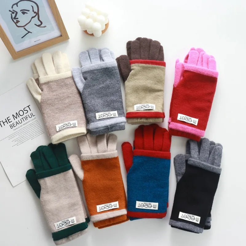 Eight pairs of fleece-lined knit gloves in assorted colors, including beige, gray, brown, pink, red, green, orange, blue, and black, arranged on a white surface with a small decorative frame and paper.