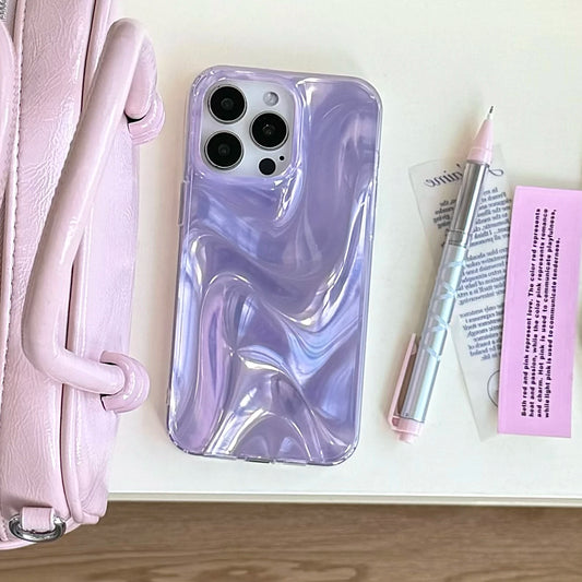 A light purple phone case with a glossy marbled swirl pattern, shown on a phone. The phone is styled in a flat-lay arrangement on a white surface next to a pink handbag, a silver pen, and a pink note card.