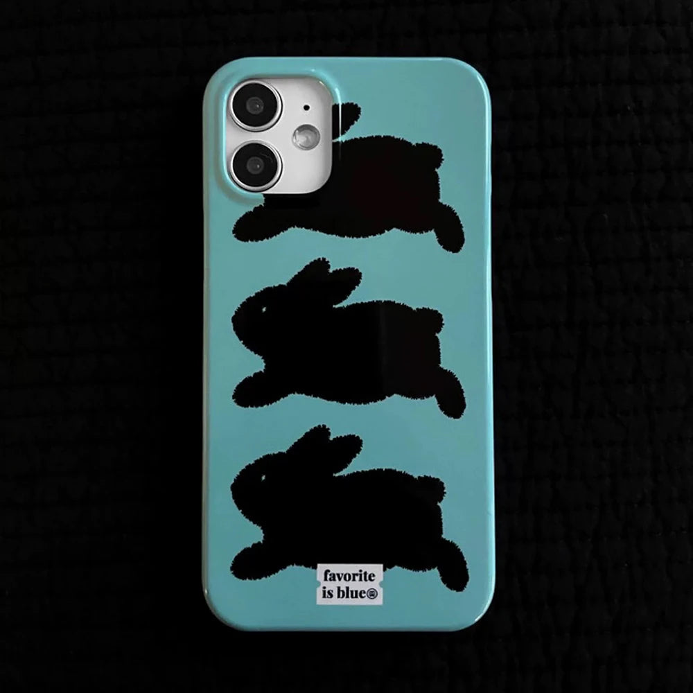 A light blue phone case featuring three black rabbit silhouettes stacked vertically, with a small white label at the bottom that reads 'favorite is blue'. The case is shown on a black textured background.