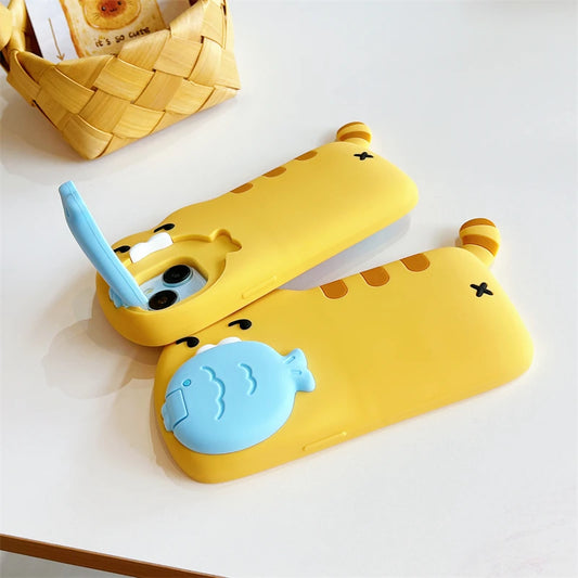 Two yellow cartoon phone cases with blue accents, featuring a cat-face design and a fish-shaped camera cover, displayed on a white surface with a woven basket in the background.