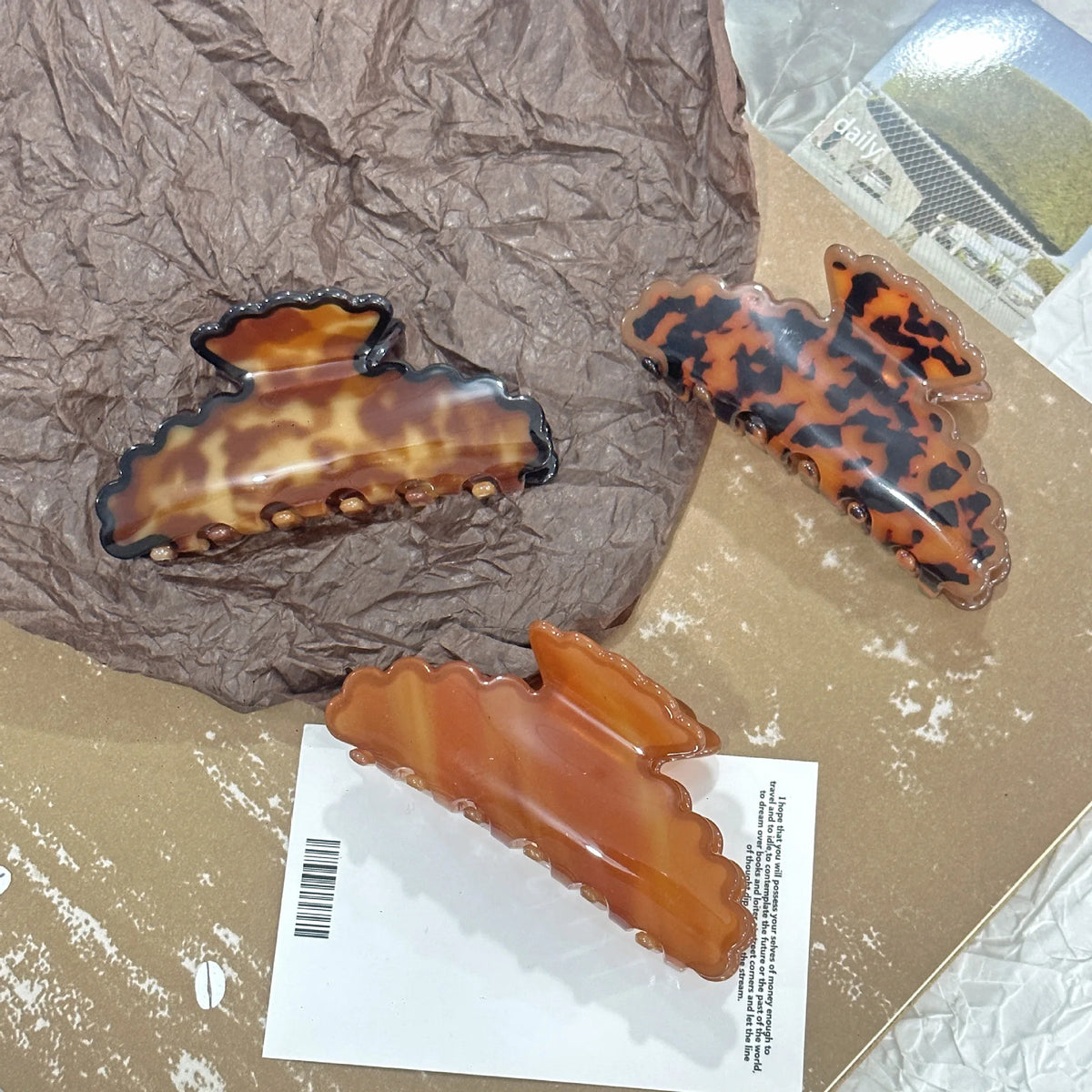 Three tortoiseshell hair clips on a crumpled brown paper background