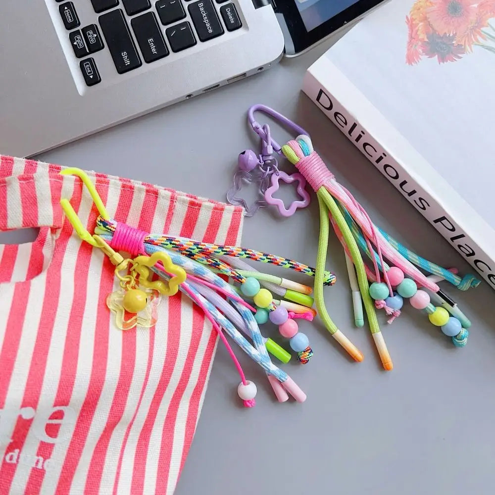 Colorful tassel keychain on a striped bag with a laptop and book in the background
