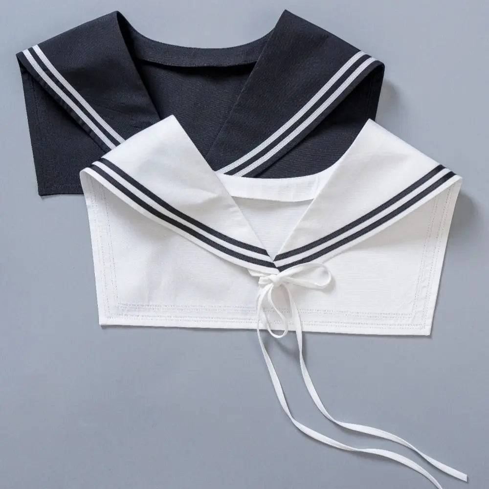 Two sailor-style collars laid flat on a gray background, one black with white stripes and one white with black stripes, both featuring tie details at the neckline.