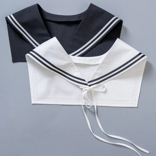 Two sailor-style collars laid flat on a gray background, one black with white stripes and one white with black stripes, both featuring tie details at the neckline.