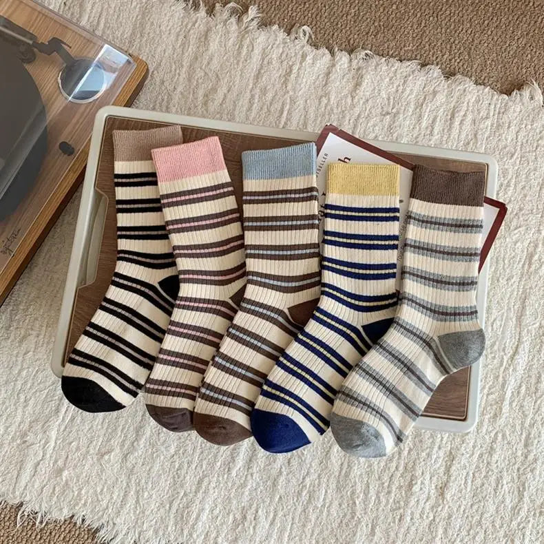 Set of striped socks on a wooden tray with a textured rug background