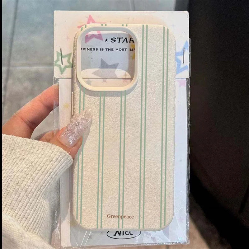 A hand wearing a cream knit sleeve holds a packaged phone case. The case has a textured cream background with thin mint green vertical stripes and a clear camera cutout.
