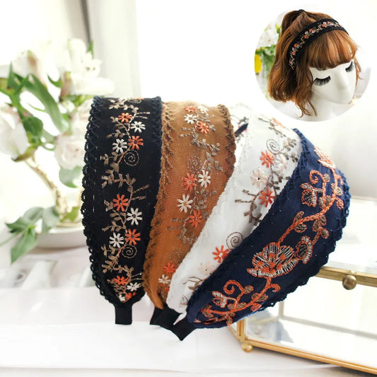 Set of embroidered headbands on a white surface with a blurred floral background