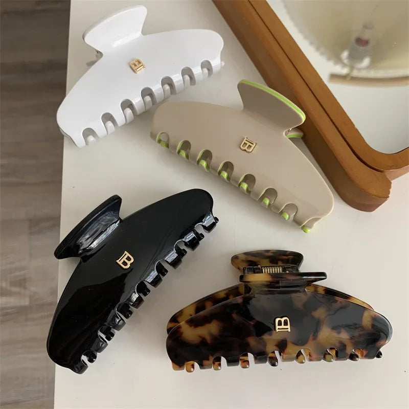 Four hair clamps in different designs on a light surface with a mirror in the background.
