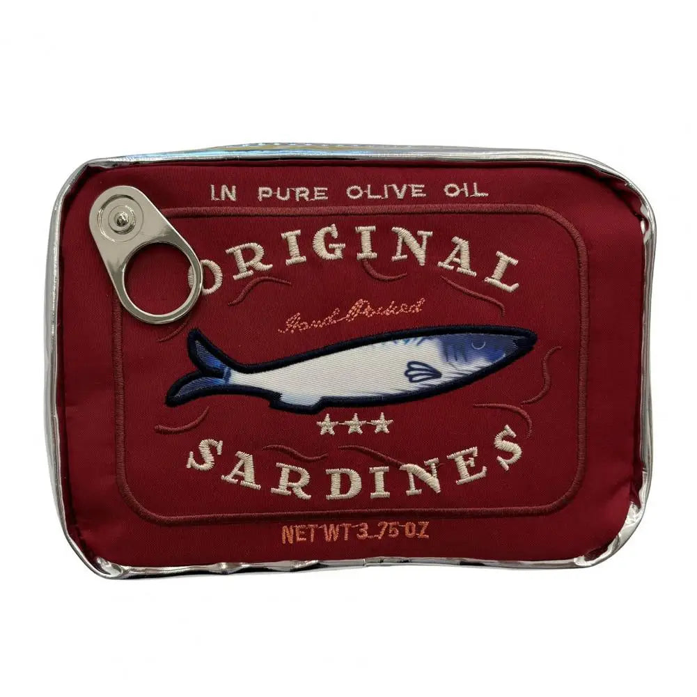 A novelty pouch designed to look like a can of sardines, featuring a deep red fabric body with embroidered text and a fish illustration, complete with a silver metal pull tab on a white background.