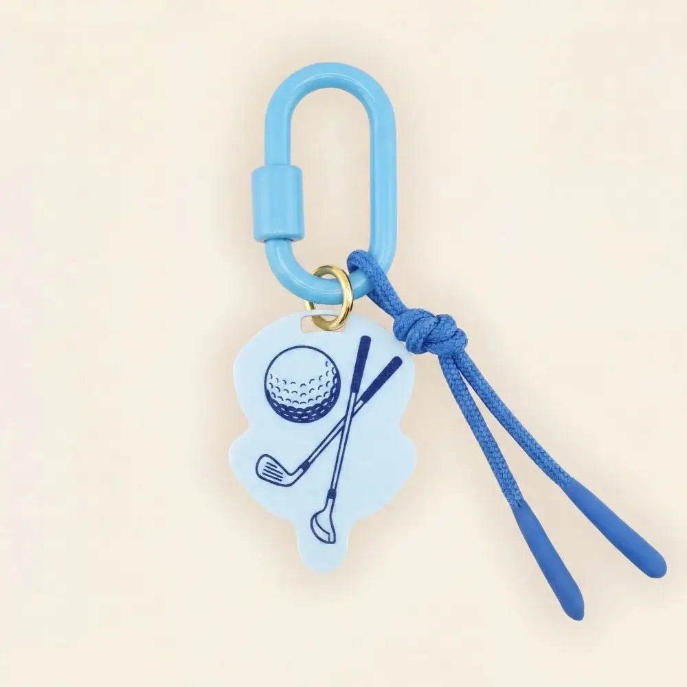 A golf-themed keychain or bag charm with a light blue carabiner, blue cord, and a light blue silhouette charm printed with a golf ball and crossed clubs, shown on a plain beige background.