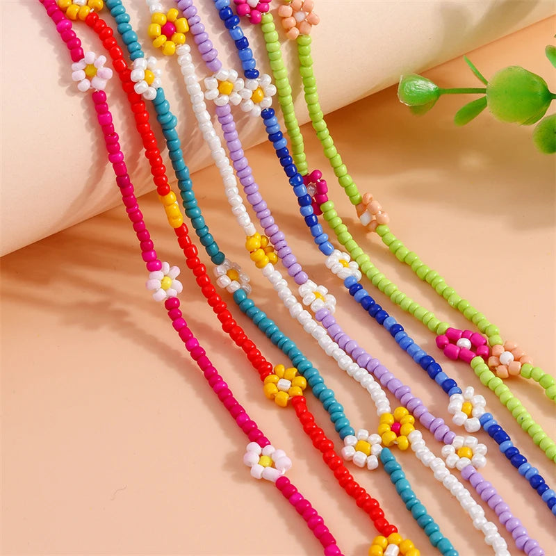 Colorful beaded necklaces with floral designs on a beige surface.