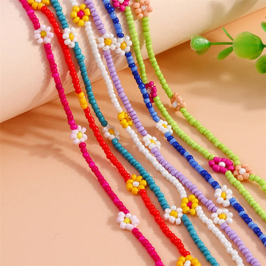 Colorful beaded necklaces with floral designs on a beige surface.
