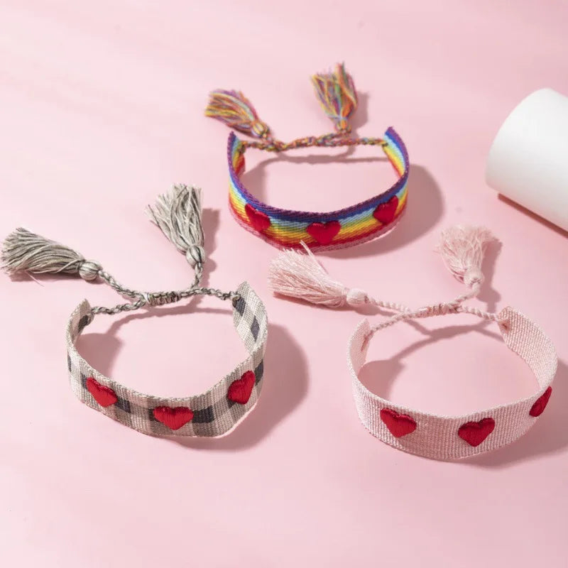 Three colorful bracelets with heart patterns on a pink background