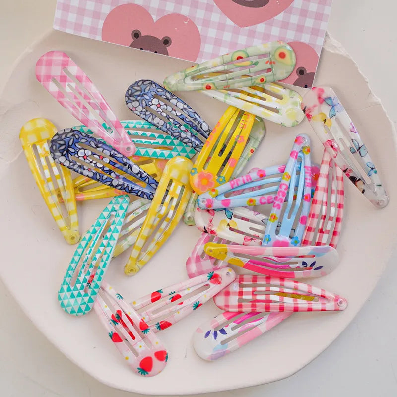 A collection of colorful plastic hair clips with various patterns including gingham, triangles, polka dots, and floral prints, arranged on a white plate.