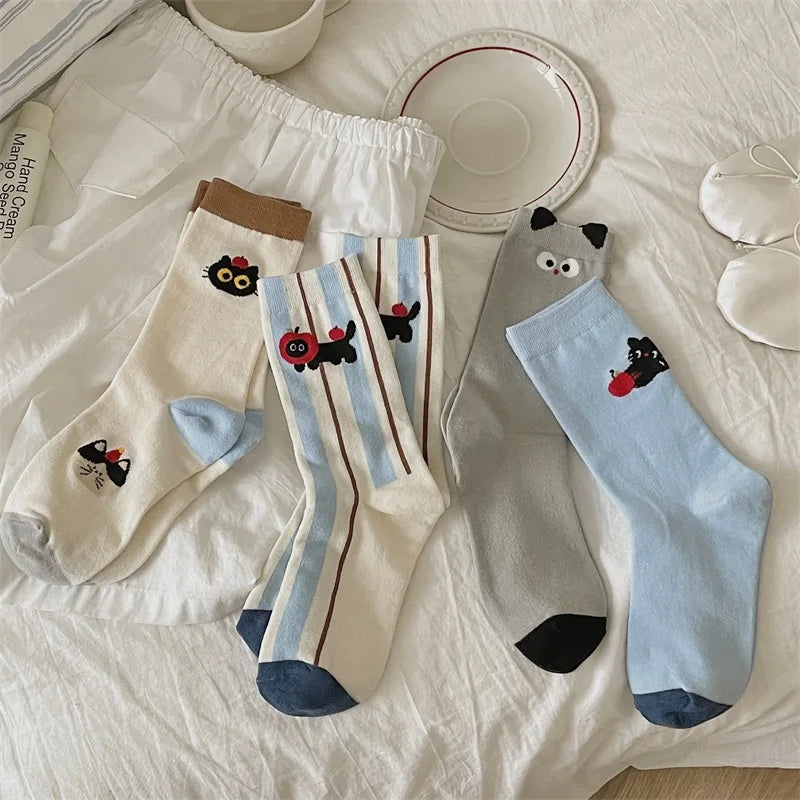 Four pairs of socks with cartoon cat designs on a white surface