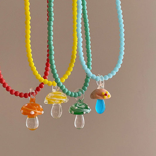 Colorful beaded necklaces with mushroom-shaped charms on a brown background