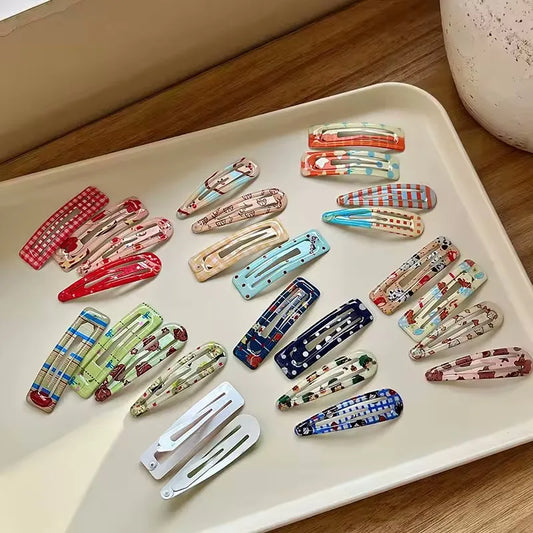 A set of 20 hair claw clips with various colorful patterns, including stripes, polka dots, and floral prints, arranged on a beige tray.