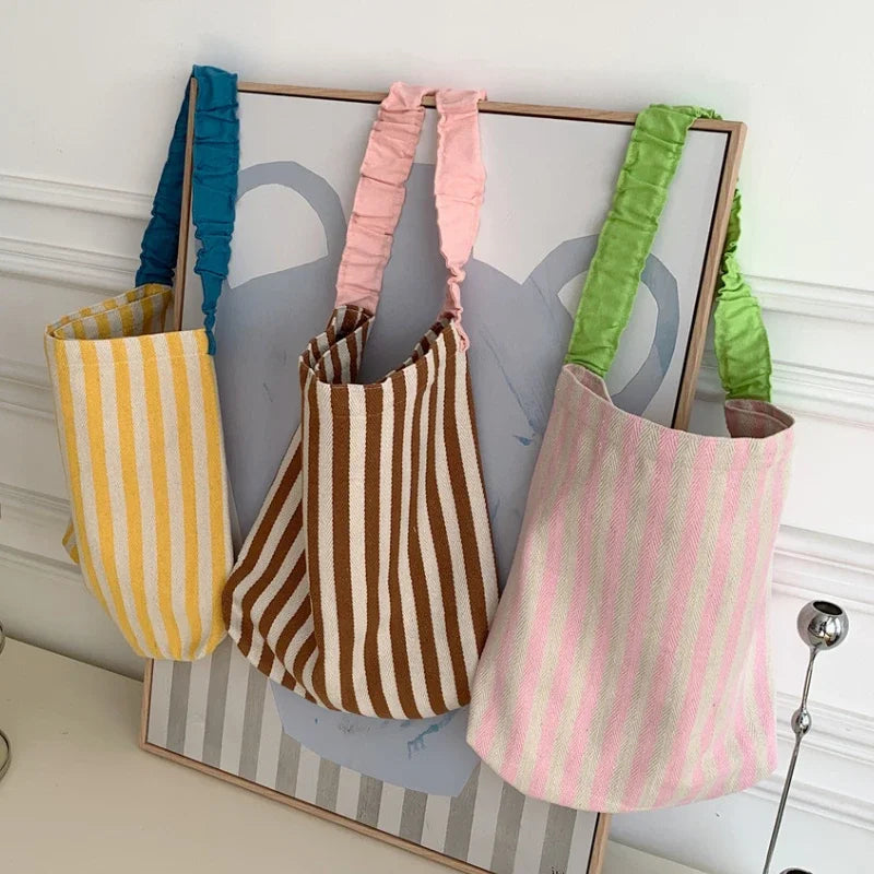 Three colorful striped bags hanging on a frame against a white wall.