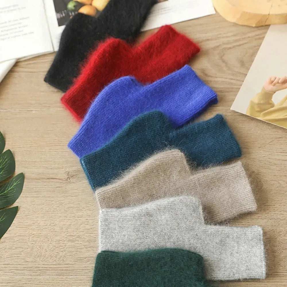 Set of colorful knitted fingerless gloves on a wooden surface.
