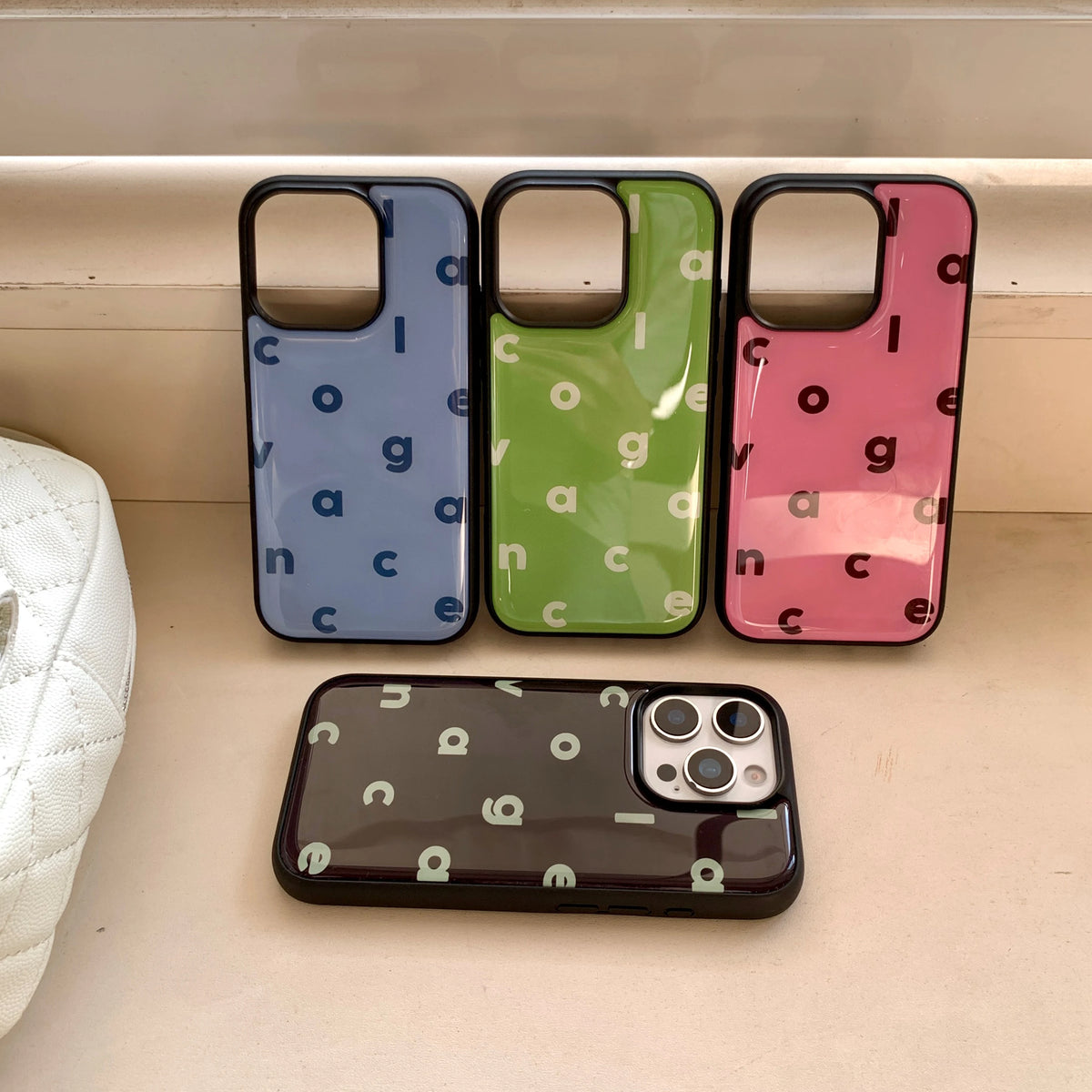 Four phone cases with letter patterns on a wooden surface