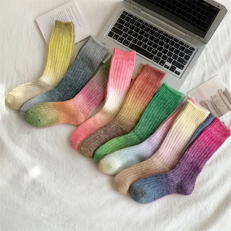 Colorful gradient socks on a white surface with a laptop in the background