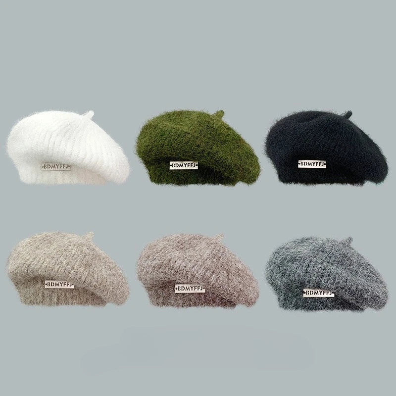 Six fuzzy knit berets in different colors are arranged in a 2x3 grid on a plain light gray background. The berets are white, olive green, black, light beige, taupe, and heather gray.