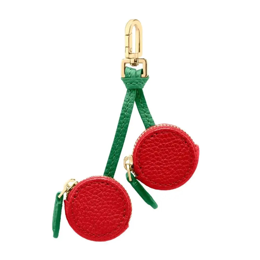 Red and green cherry pouches with gold clasps on a white background