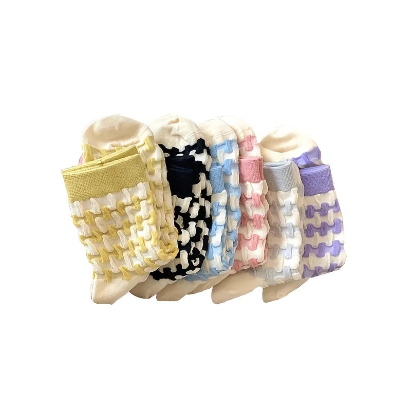 Six pairs of baby socks in assorted colors, including yellow, black and white, light blue, pink, gray, and purple, arranged in a fan shape on a white background.