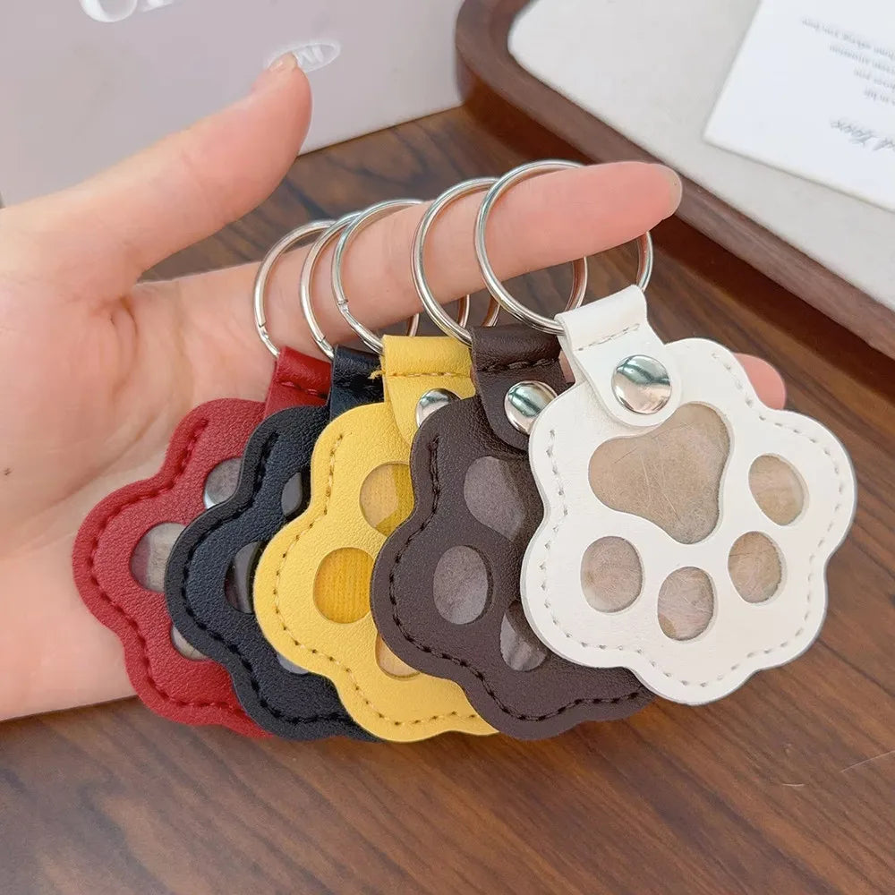 Set of paw-shaped keychains in various colors held by a hand.