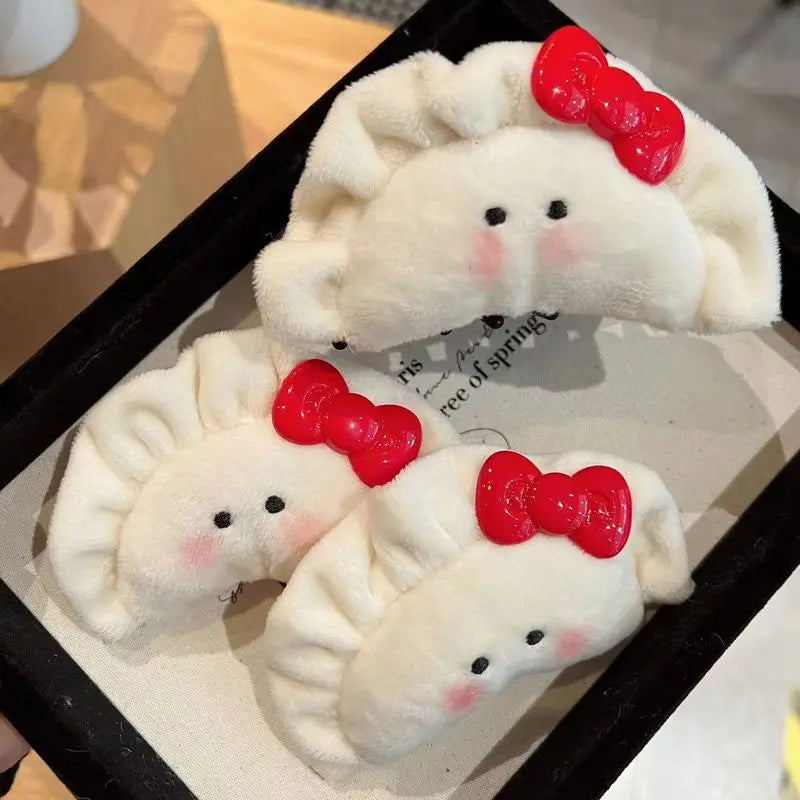 Three plush dumplings with red bow ties on a black tray.