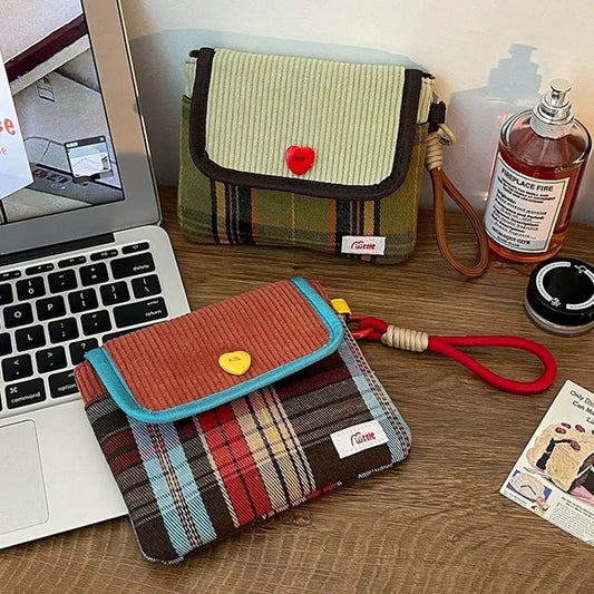 Two fabric pouches on a desk next to a laptop and a bottle of perfume.