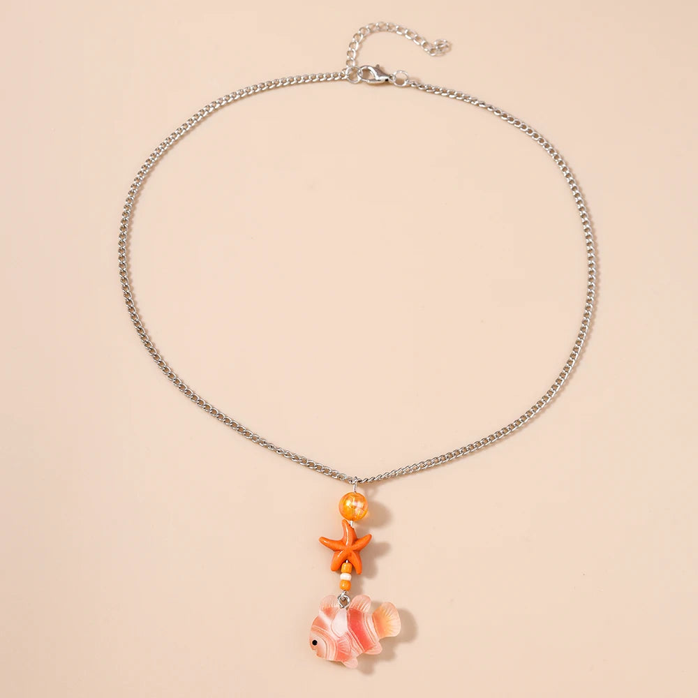 Necklace with fish and starfish charms on a beige background