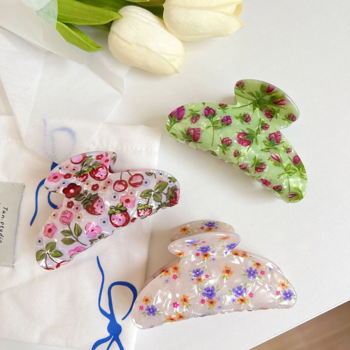 Floral-patterned hair clips on a white surface with tulips in the background