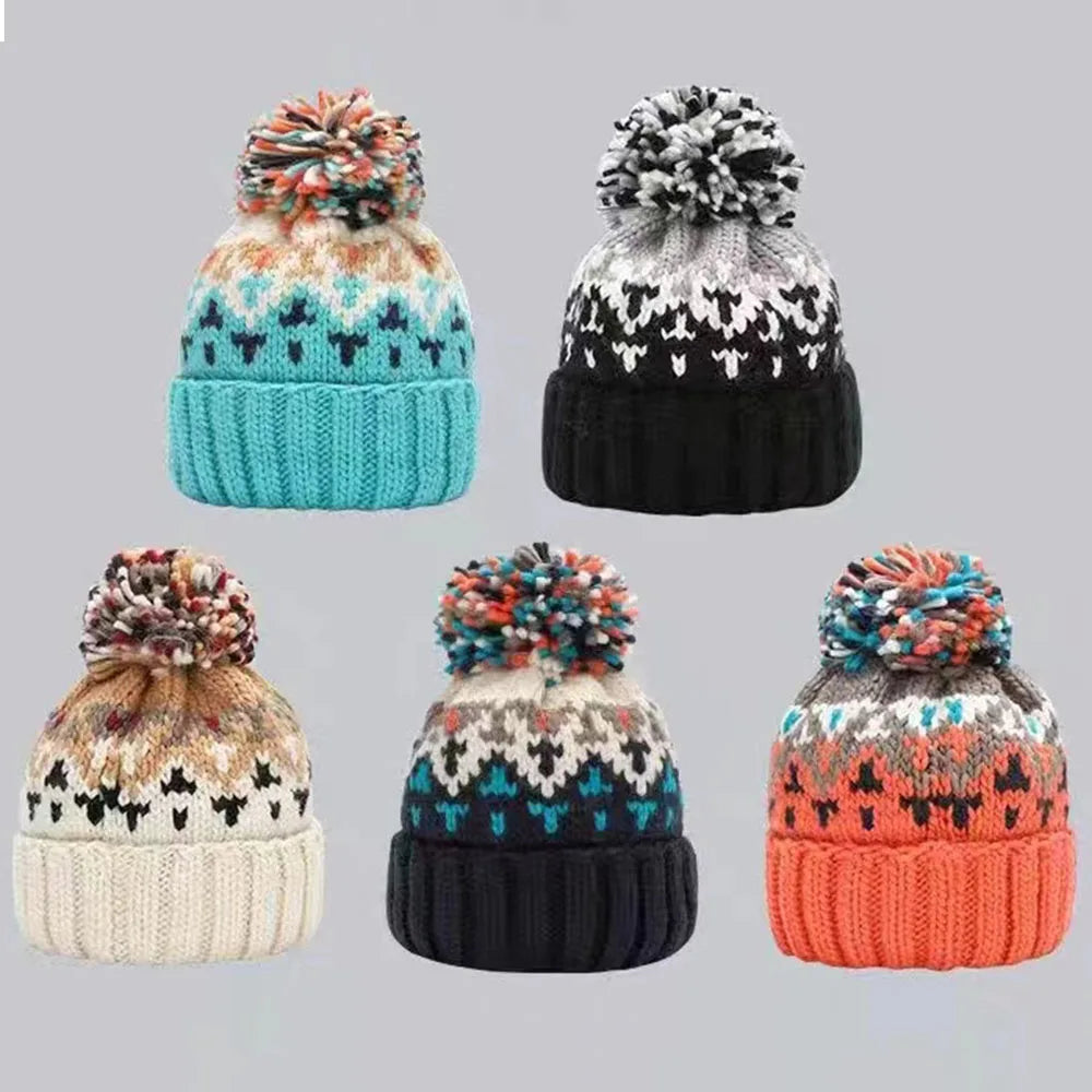 Five knit hats with patterned designs and pom-poms on a gray background