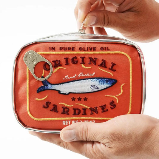 Red sardine can-shaped pouch with fish illustration held by a hand