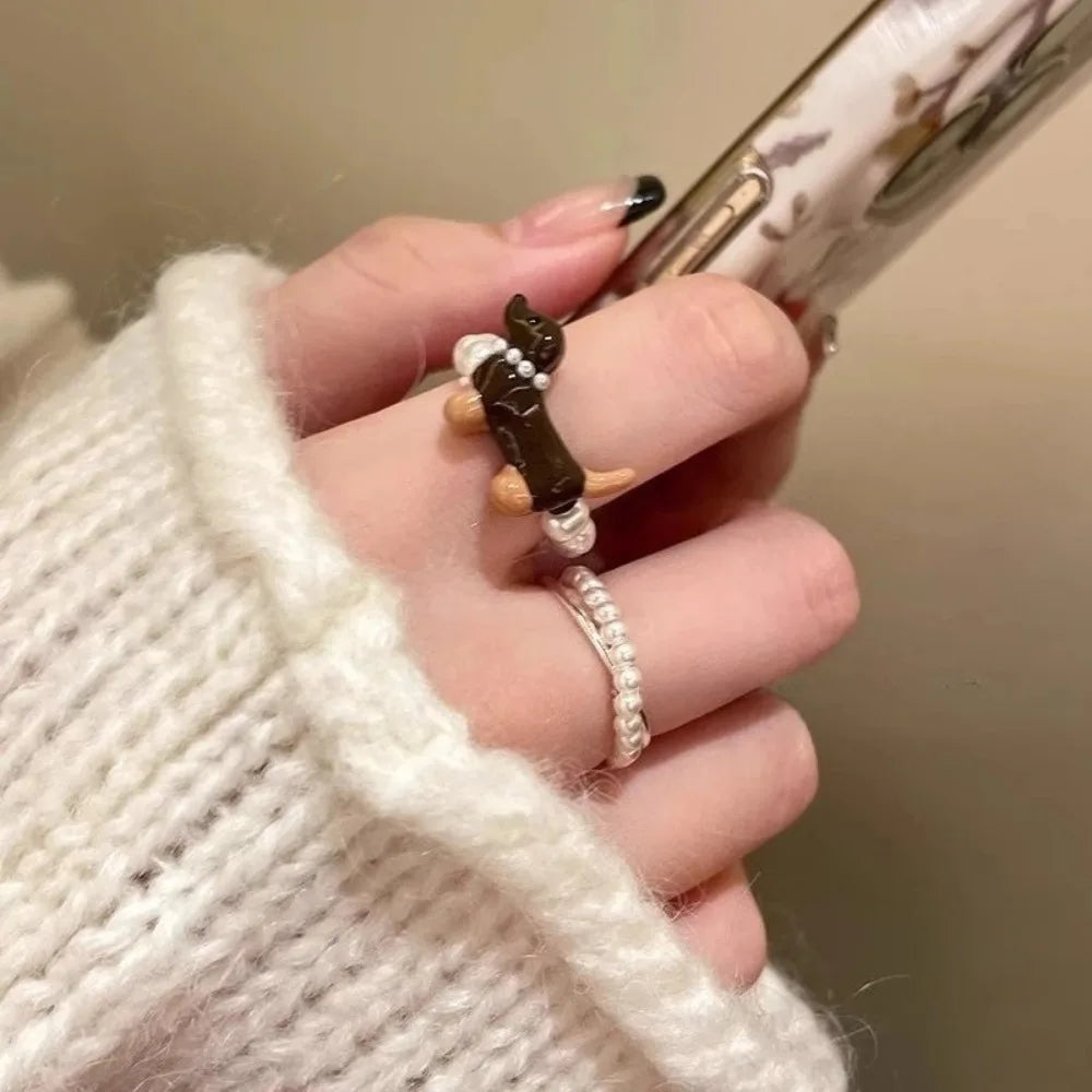 Hand wearing a small animal-shaped ring with a plain background
