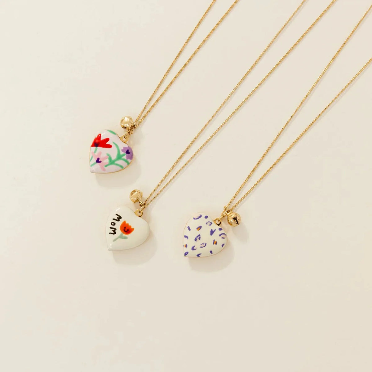 Three necklaces with heart-shaped pendants on a beige background