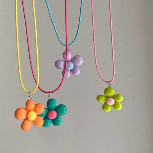 Three colorful flower necklaces on a gray background
