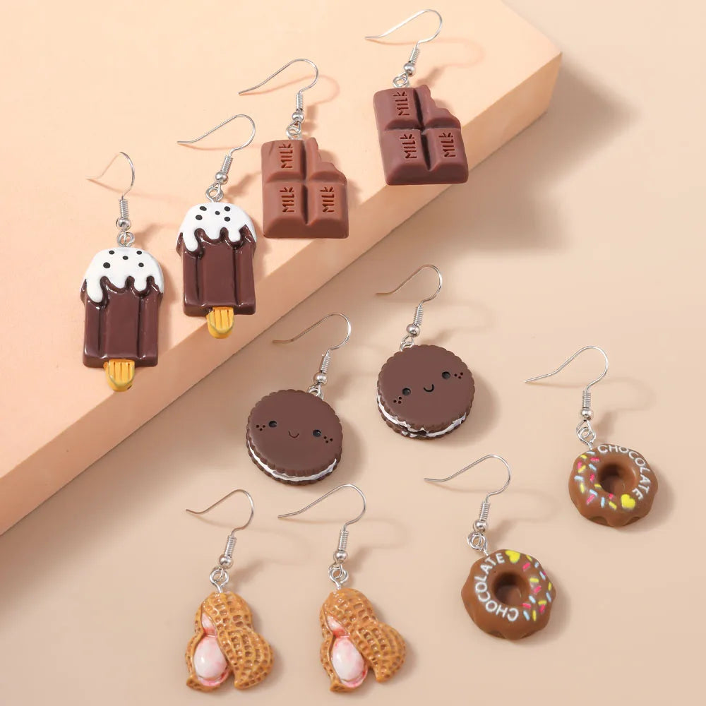 Various chocolate-themed earrings on a beige background