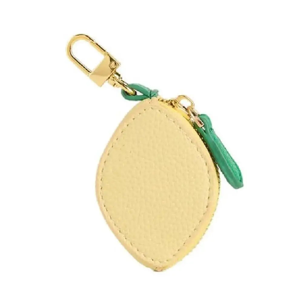 Yellow lemon-shaped keychain with gold clasp and green zipper on a white background