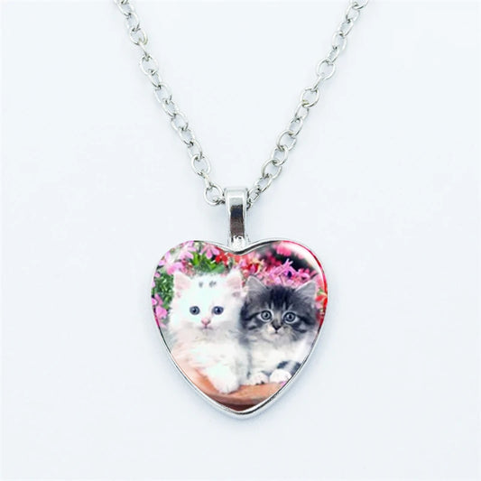 Heart-shaped pendant with two kittens on a floral background, attached to a silver chain.
